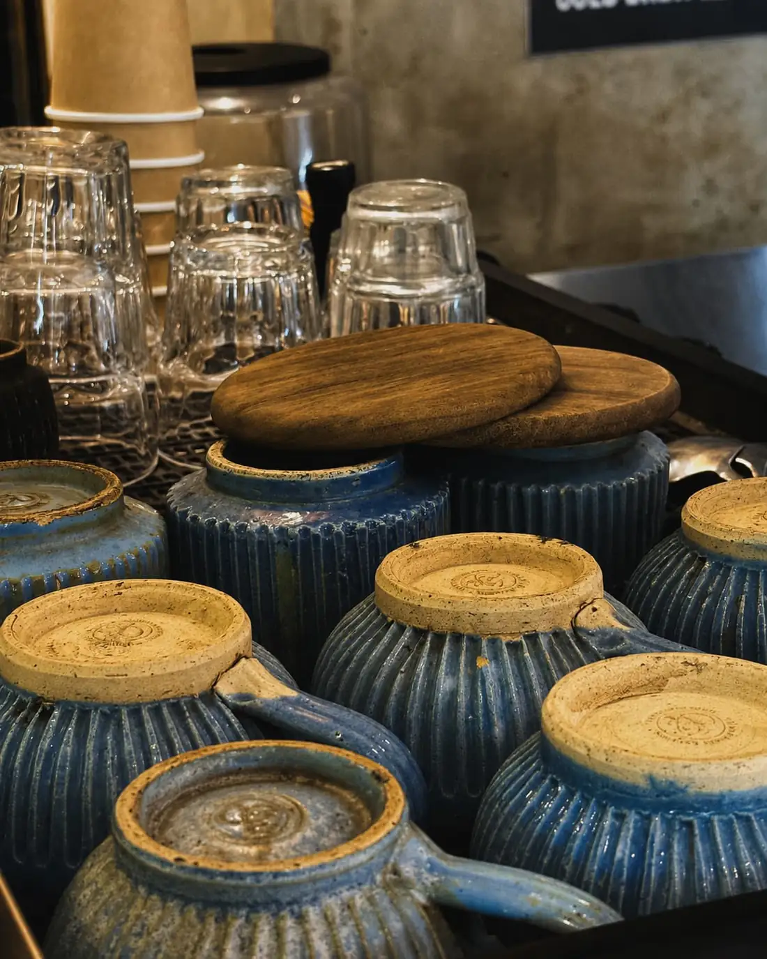 A tray of blue-glazed stoneware cups stacked upside down beside the coffee machine.